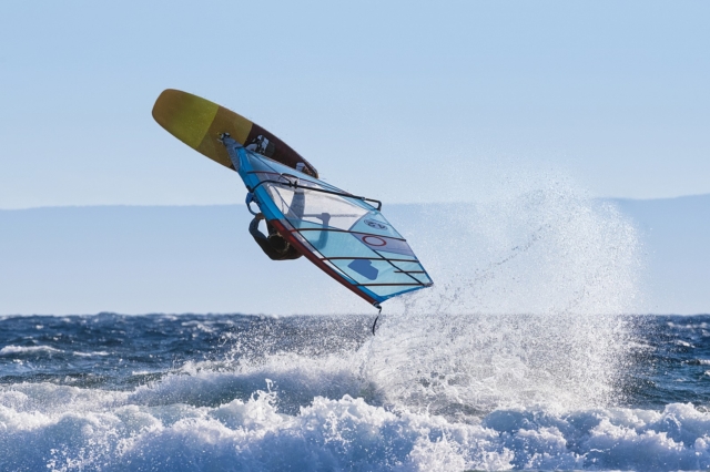 Young Windsurfer Jumping Wave on Windsurf Board