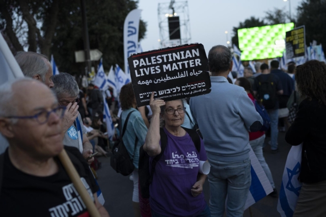 Γυναίκα στο Ισραήλ κρατάει πλακάτ που γράφει "Οι ζωές των Παλαιστινίων μετράνε" σε διαδήλωση έξω από την Κνέσετ