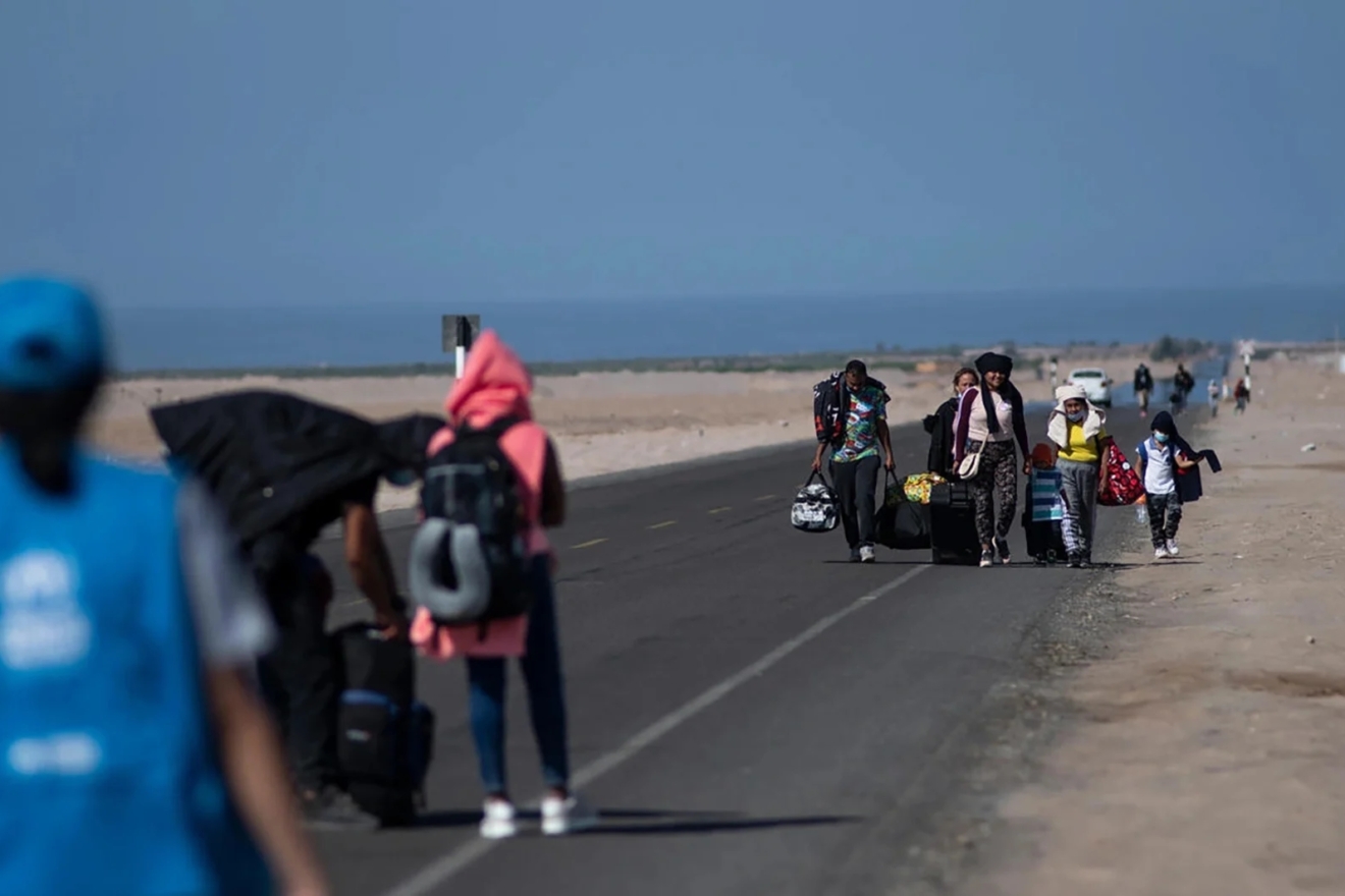 Μια οικογένεια από τη Βενεζουέλα περπατάει στον αυτοκινητόδρομο που βρίσκεται παράλληλα στο σύνορο με τη Χιλή στις 3 Δεκεμβρίου 2021 στην νότια περιοχή Tacna του Περού.