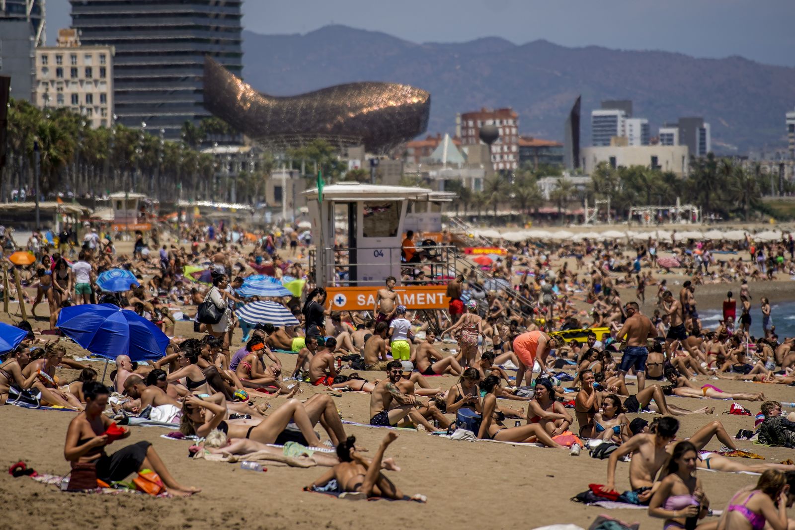 Τουρίστες κάνουν ηλιοθεραπεία στην παραλία της Βαρκελώνης