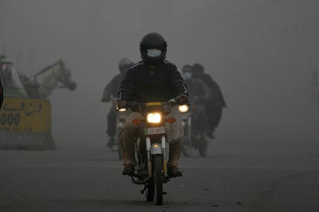 Μοτοσικλετιστές κινούνται με προβολείς το πρωί λόγω αιθαλομίχλης στη Λαχόρη του Πακιστάν